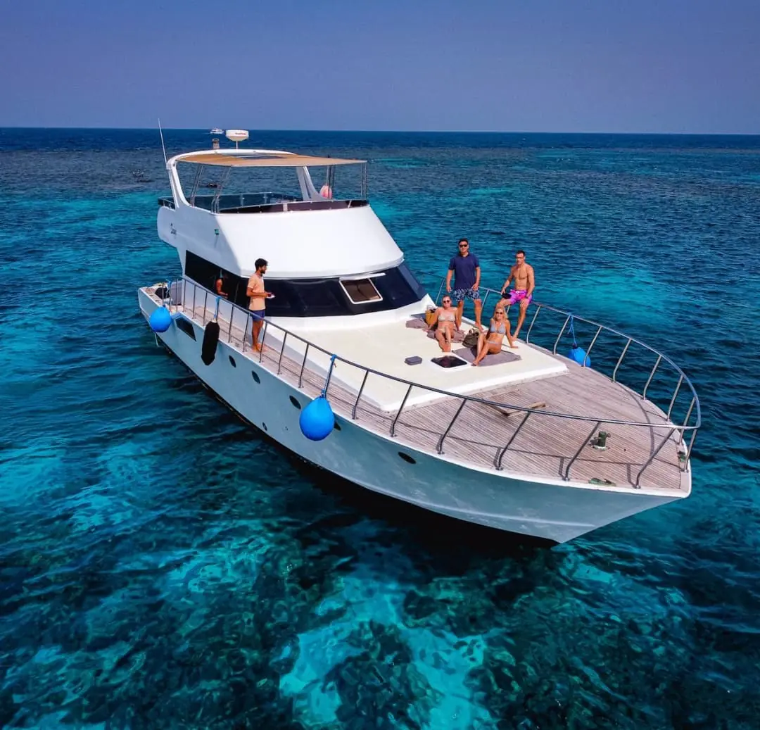 Guests on a yacht anchored above turquoise reefs in the Red Sea