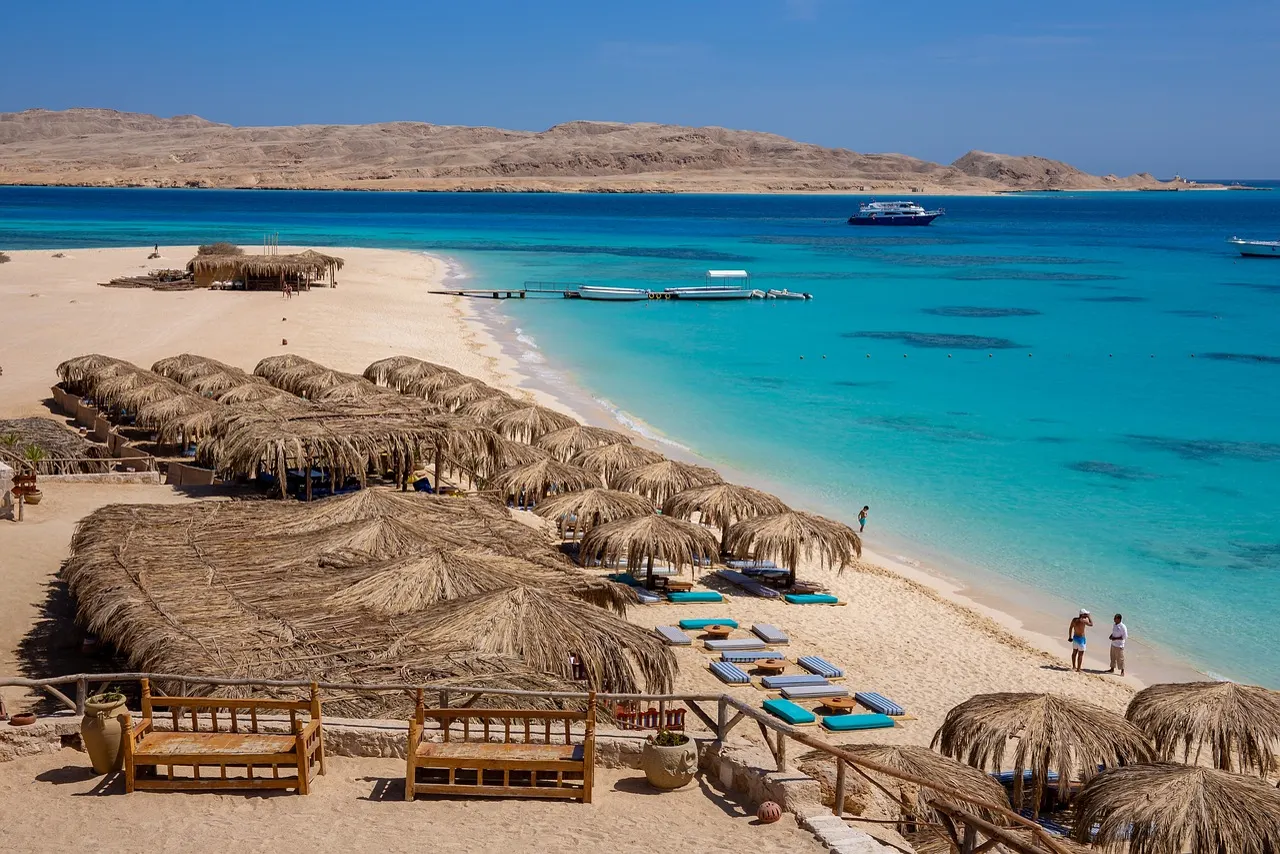 White sand, straw parasols and turquoise water at Orange Bay Island